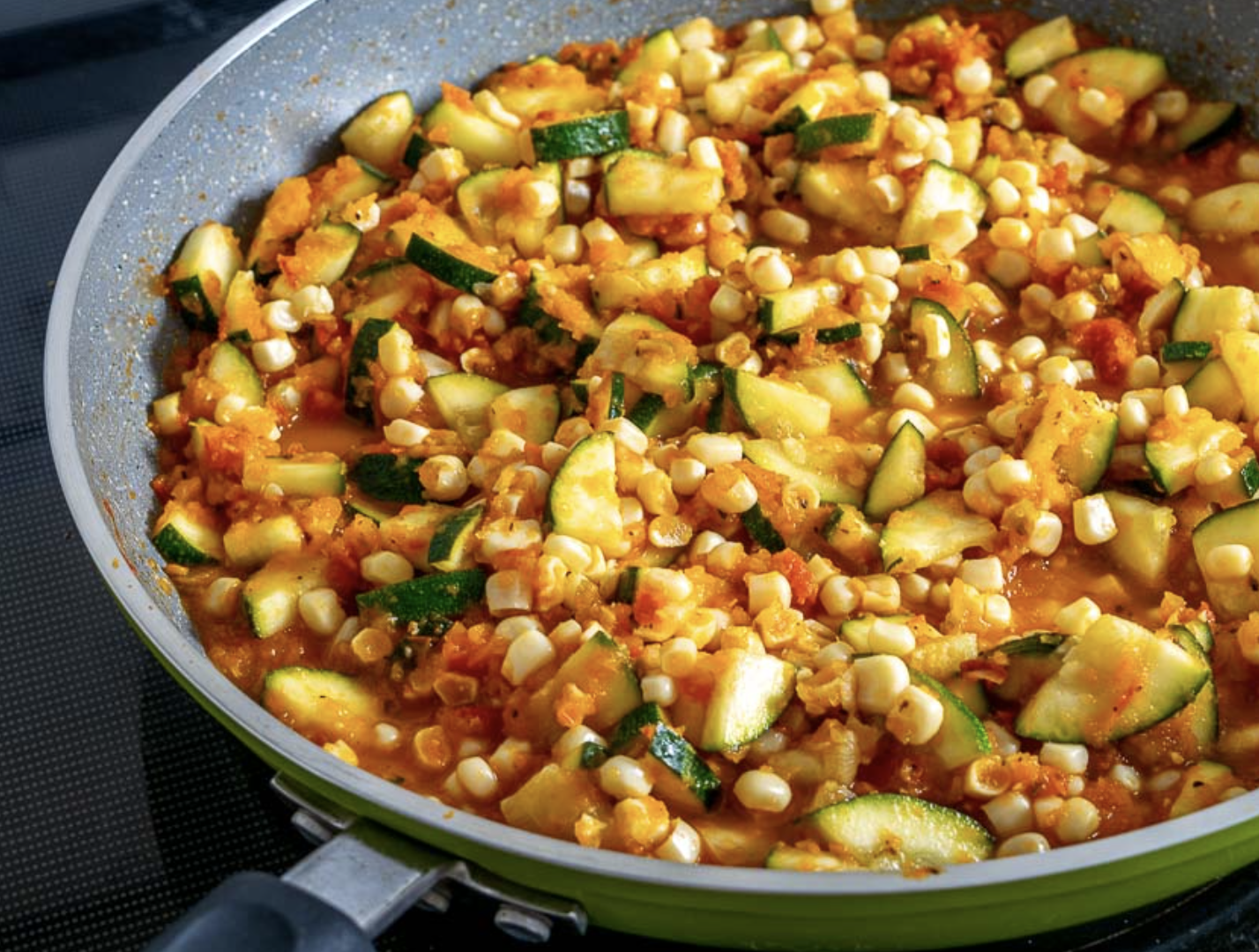 Fresh ingredients for calabacitas recipe, including zucchini, corn, peppers, and tomatoes.